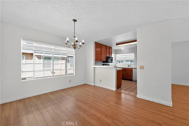 a kitchen with stainless steel appliances granite countertop a stove top oven a sink dishwasher and a refrigerator with wooden floor