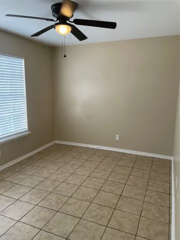 a view of an empty room and chandelier fan