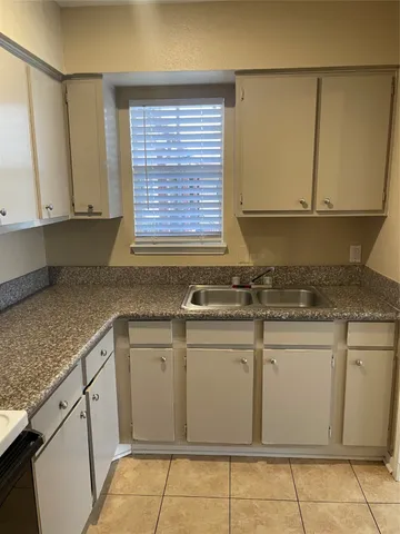 a kitchen with granite countertop cabinets sink and white appliances