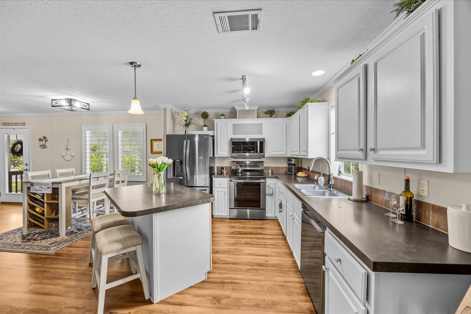 121 Southeast Paradise Place Stuart, FL 34997 - Photo 4 of 33 a kitchen with stainless steel appliances granite countertop a sink a stove top oven a counter space and cabinets