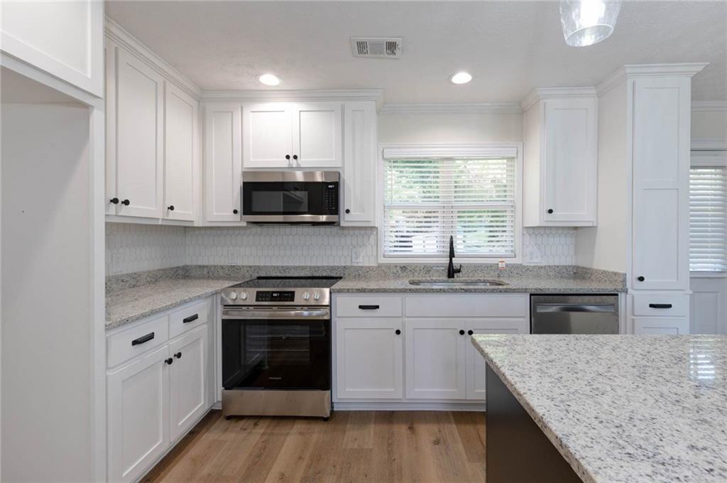 2899 Lamb Road Smiths Station, AL 36877 - Photo 9 of 26 Kitchen featuring white cabinetry, stainless steel appliances, granite countertops, and wood-finish flooring