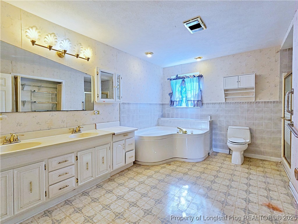 1459 Crawford Wright Road Raeford, NC 28376 - Photo 21 of 50 a spacious bathroom with a double vanity sink toilet and a bathtub