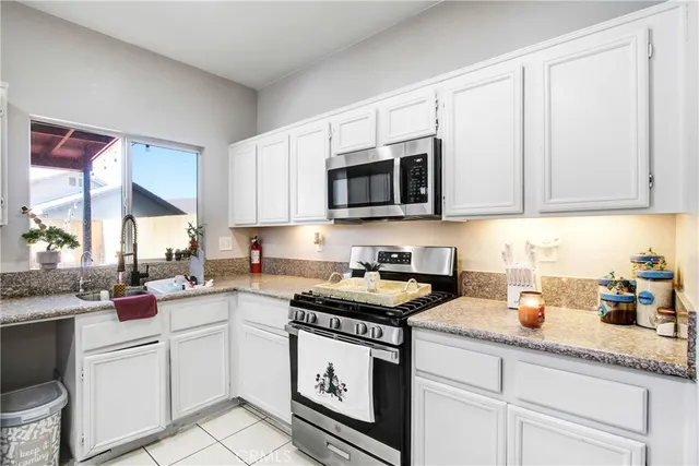 a kitchen with granite countertop white cabinets white appliances and a sink