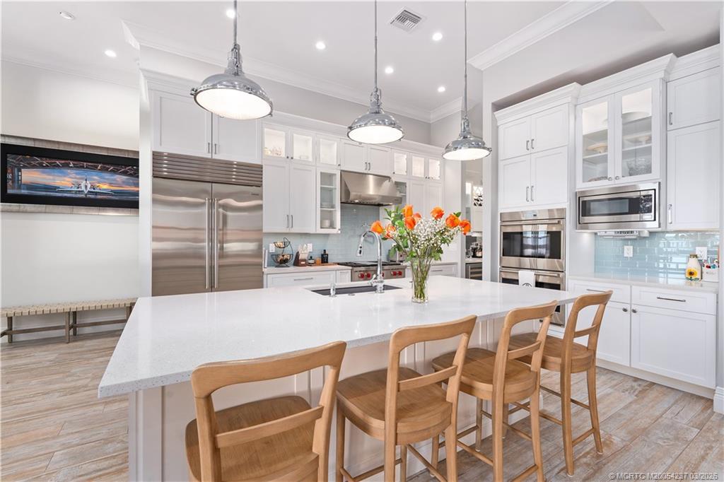 1912 Northwest Cove Circle Stuart, FL 34994 - Photo 8 of 24 a kitchen with stainless steel appliances a dining table chairs stove and sink