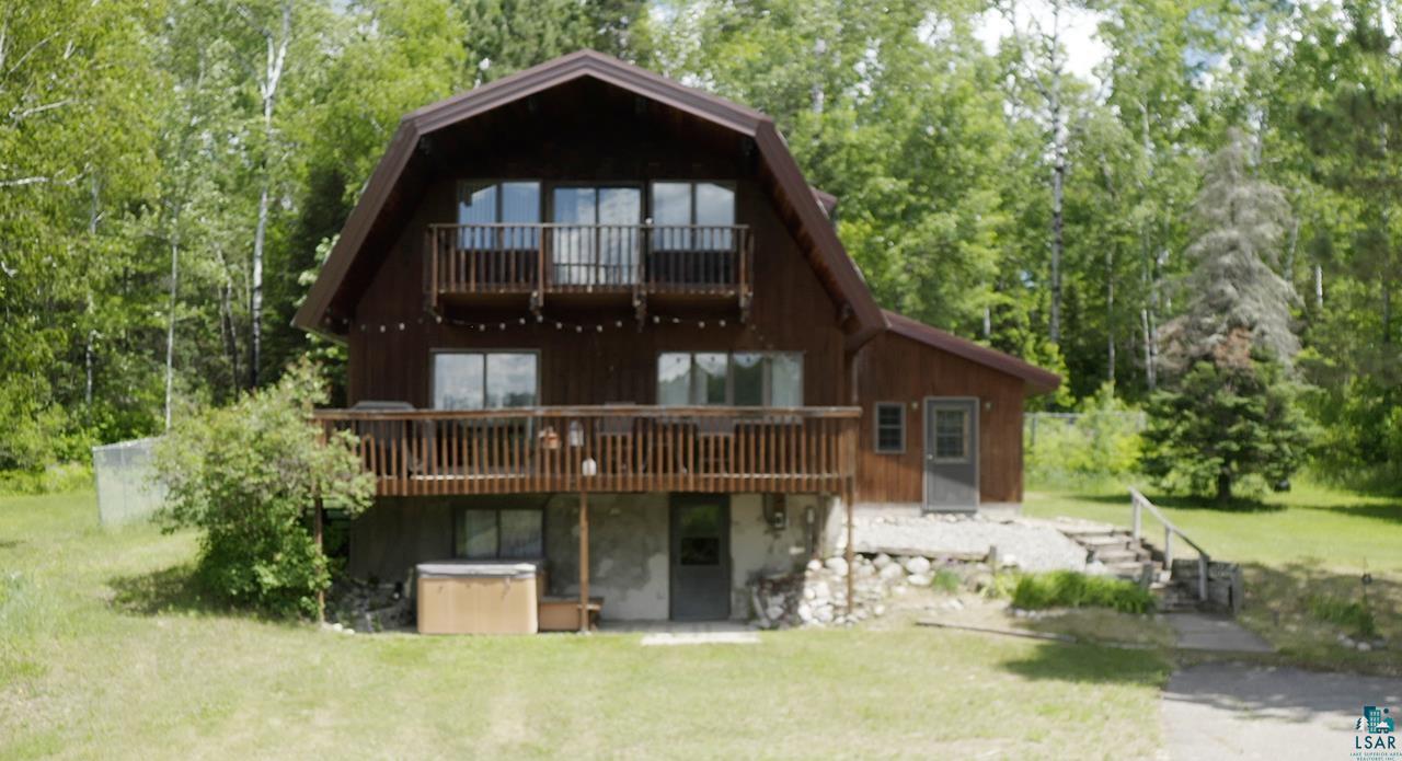 9289 Heino Road Angora, MN 55703 - Photo 37 of 37 Brown gambrel-style home featuring a second-story balcony with metal railings and a first-story wooden deck