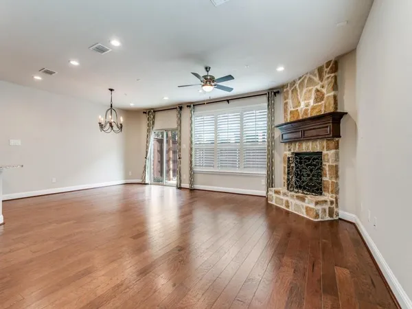 an empty room with wooden floor chandelier and windows
