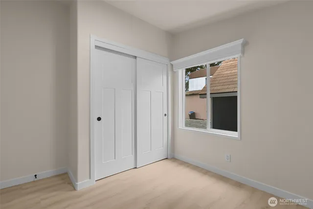 a view of an empty room with closet and mirror