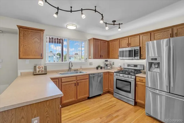 a kitchen with stainless steel appliances granite countertop a sink a stove a refrigerator cabinets and a center island