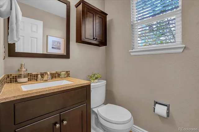 a bathroom with a granite countertop toilet sink and mirror