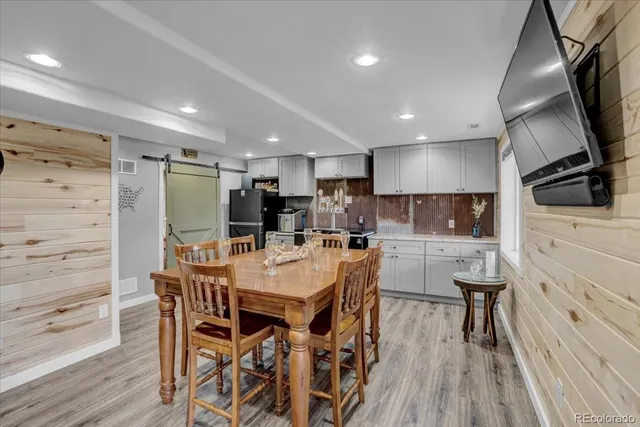 a kitchen with stainless steel appliances kitchen island granite countertop a refrigerator a sink a stove and white cabinets with wooden floor