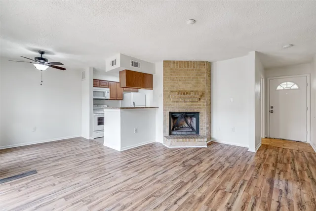a view of empty room with a fireplace and wooden floor