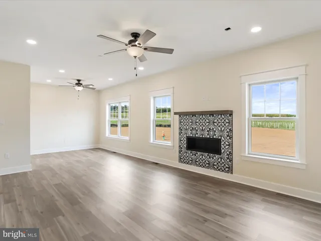 a view of an empty room with wooden floor and a ceiling fan