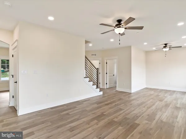 an empty room with wooden floor fireplace and windows