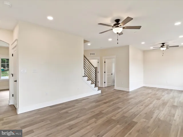 an empty room with wooden floor fireplace and windows