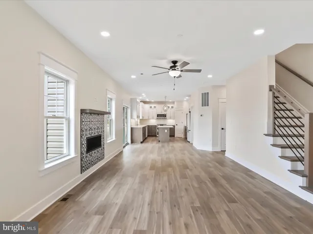a view of an empty room with wooden floor and a ceiling fan