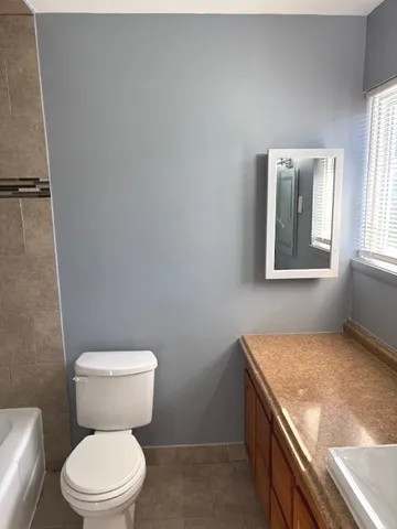 a bathroom with a granite countertop toilet and a sink