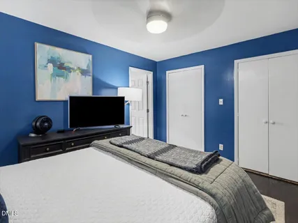 a bedroom with a bed and a flat tv screen on dresser