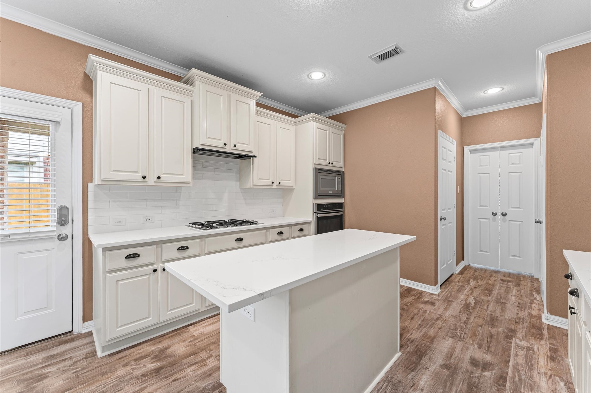 1615 Noble Pointe Drive Spring, TX 77379 - Photo 13 of 50 This kitchen features elegant countertops, white cabinetry, and stainless steel appliances, including a modern refrigerator and dishwasher. An open archway connects to the living area, enhancing the spacious feel. Neutral tones and recessed lighting add warmth and sophistication.