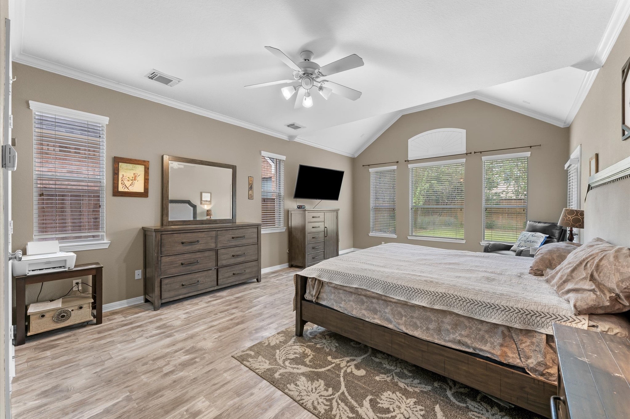 1615 Noble Pointe Drive Spring, TX 77379 - Photo 20 of 50 This spacious bedroom features a vaulted ceiling, large windows for natural light, and wood-style flooring. It includes a ceiling fan, modern furniture, and neutral tones for a cozy, inviting atmosphere.