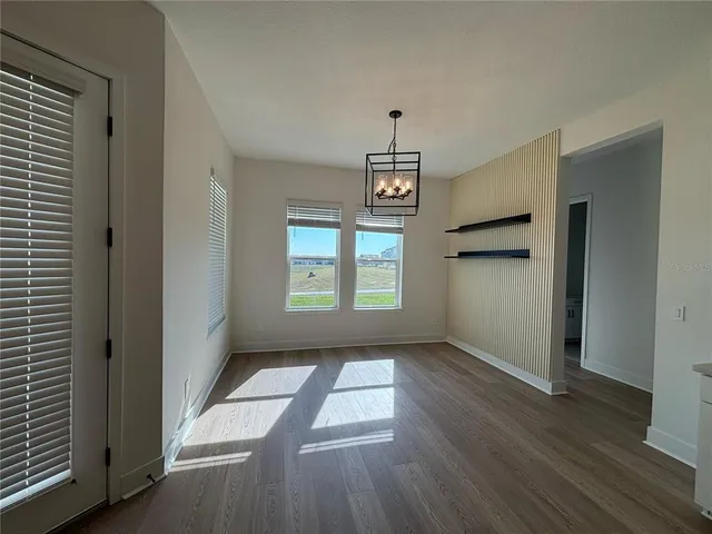 an empty room with windows and chandelier fan