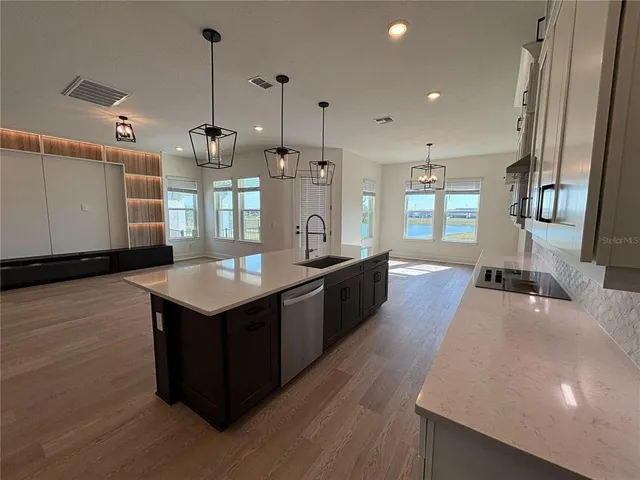 a large kitchen with stainless steel appliances a large counter top a stove a sink and a refrigerator