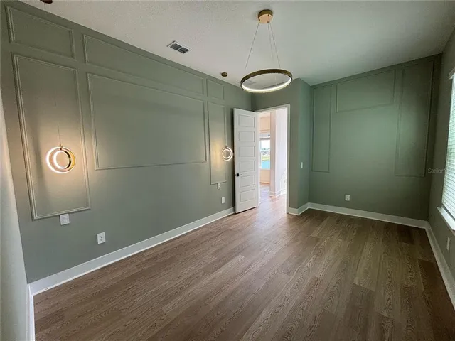 an empty room with wooden floor and mirror