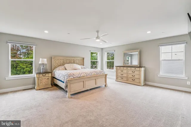 a spacious bedroom with a bed a table and windows