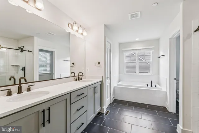 a spacious bathroom with a bathtub sink double vanity and mirror