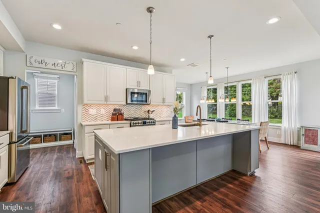 a kitchen with kitchen island a stove a sink a center island and wooden floor
