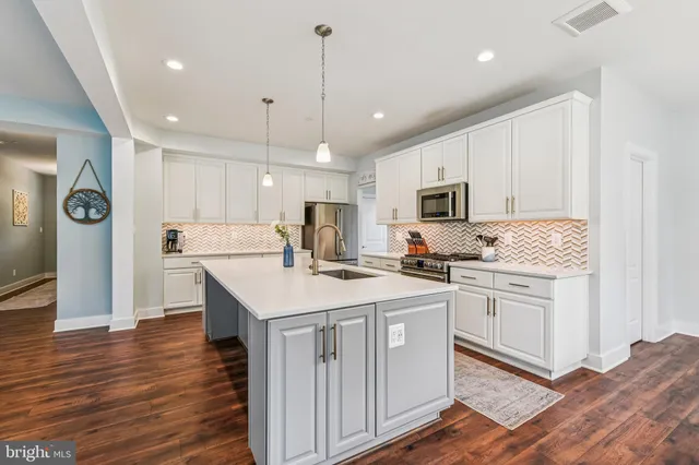 a kitchen with stainless steel appliances granite countertop a stove top oven a refrigerator a sink and dishwasher with wooden floor