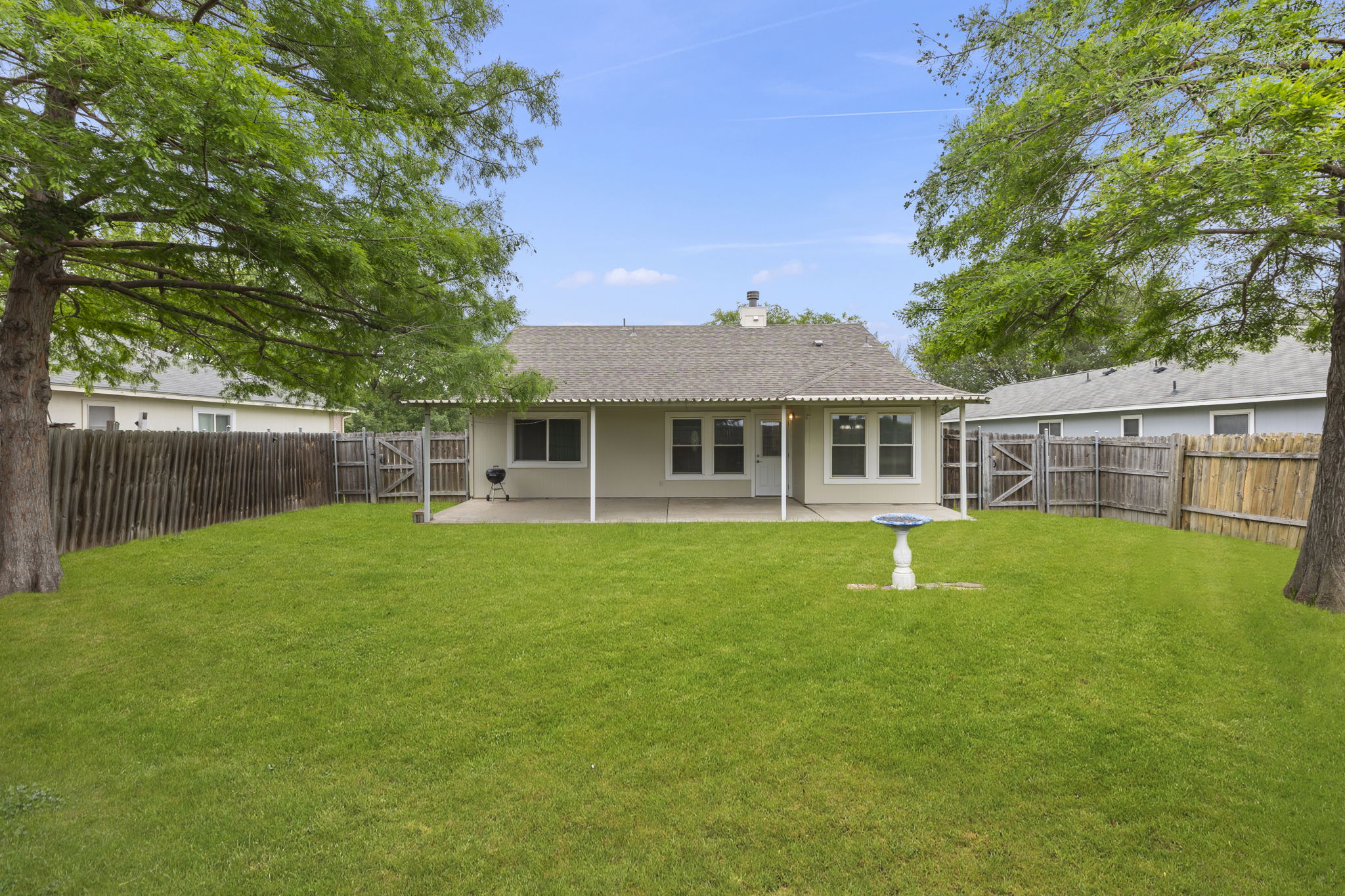 290 Bailey Loop Kyle, TX 78640 - Photo 29 of 33 Expansive green lawn with mature trees and a covered patio