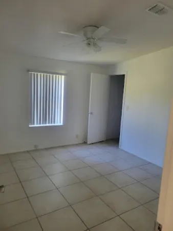 an empty room with a ceiling fan and window