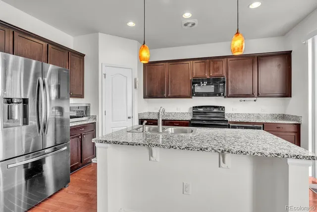 a kitchen with stainless steel appliances granite countertop a sink refrigerator and cabinets