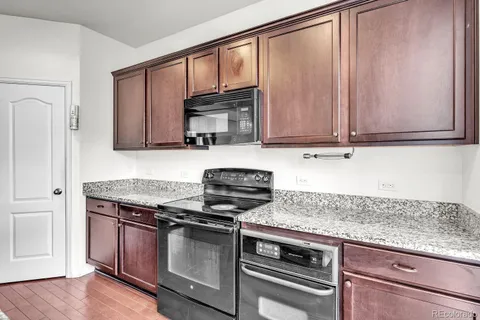 a kitchen with granite countertop cabinets stainless steel appliances and a wooden floor