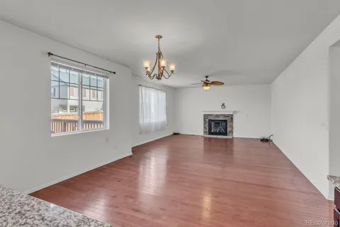 an empty room with wooden floor chandelier and windows