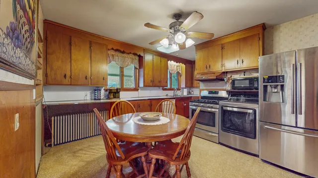 a kitchen with stainless steel appliances a table chairs and refrigerator