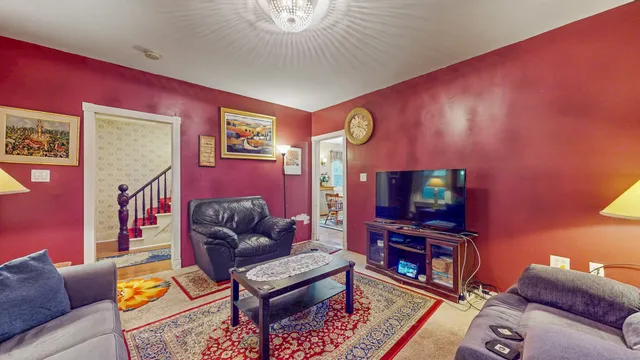 a living room with furniture and a flat screen tv with kitchen view