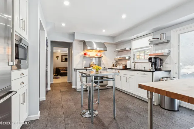 a kitchen with stainless steel appliances kitchen island granite countertop a table chairs sink and cabinets