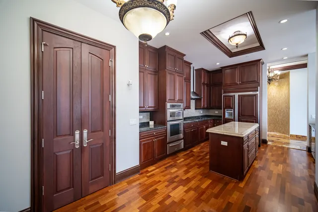 a kitchen with kitchen island wooden cabinets and refrigerator