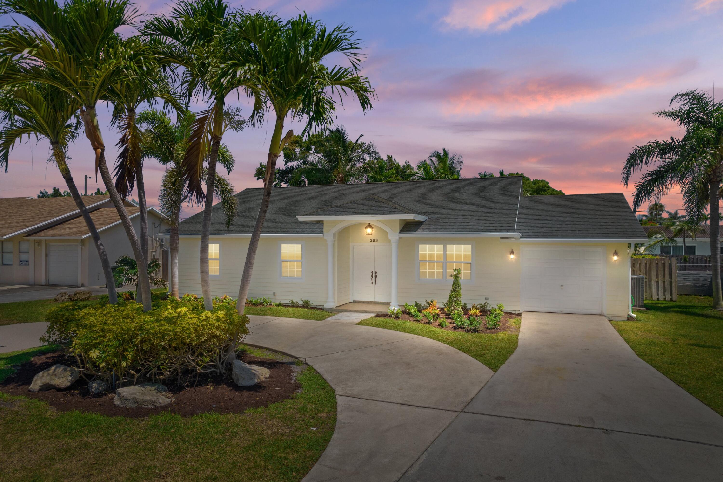 263 Northeast 24th Court Boca Raton, FL 33431 - Photo 17 of 29 a front view of a house with a yard and potted plants