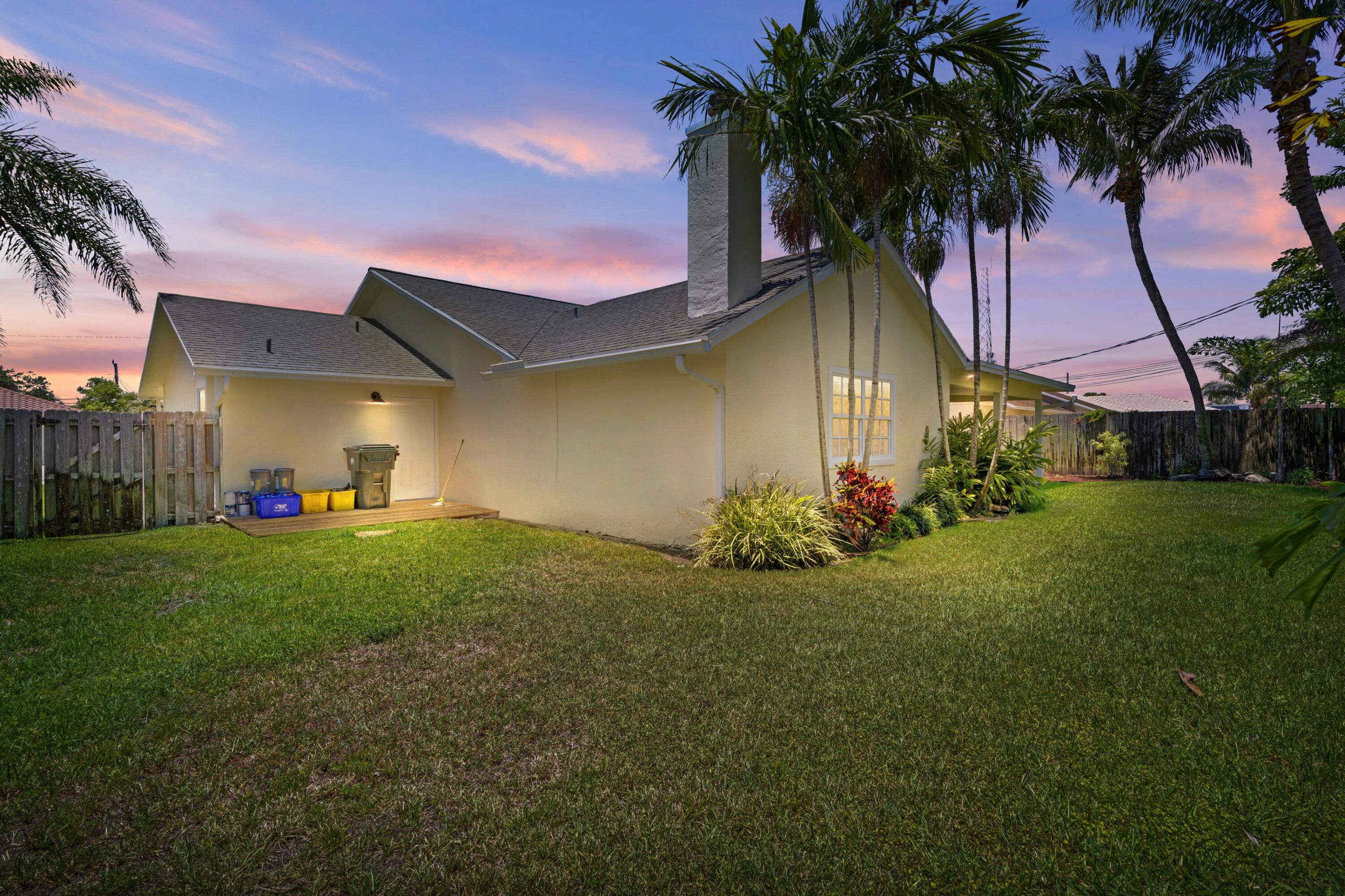 263 Northeast 24th Court Boca Raton, FL 33431 - Photo 18 of 29 a front view of yellow house with a garden