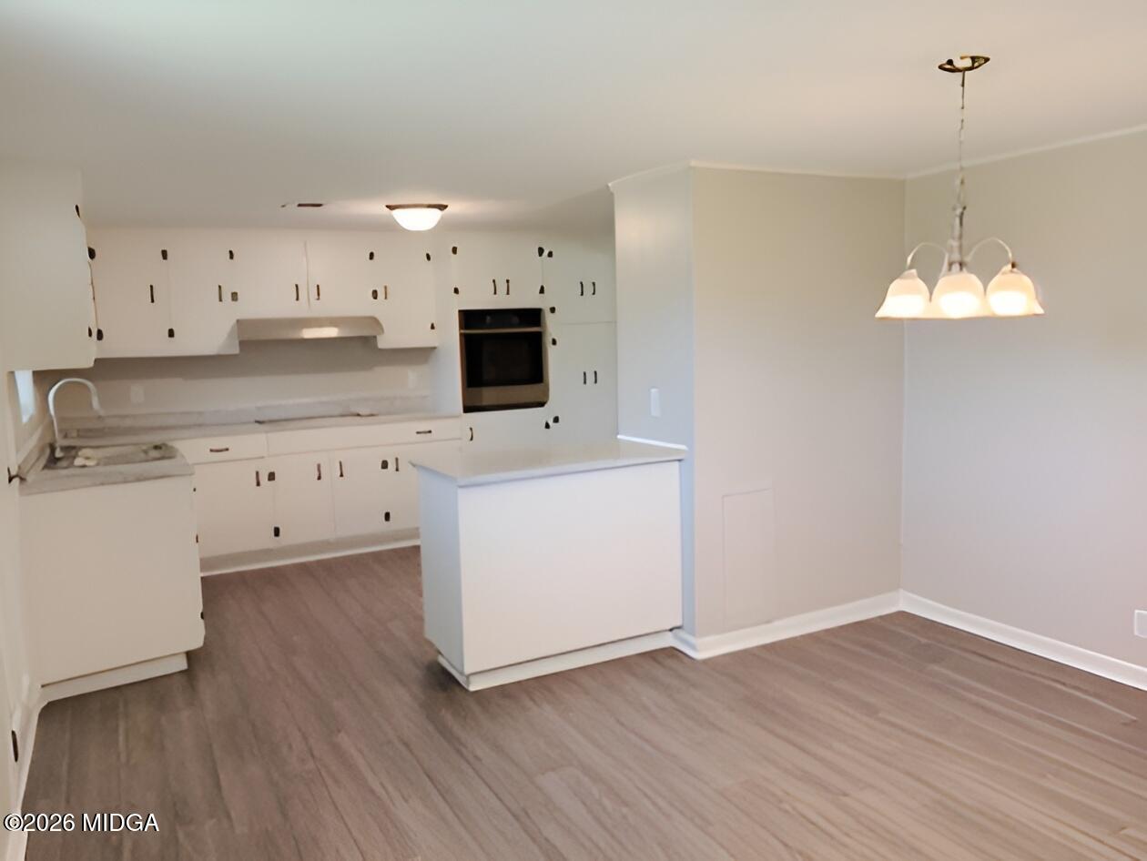 868 Mac Thompson Road Cochran, GA 31014 - Photo 6 of 31 a kitchen with cabinets wooden floor and appliances