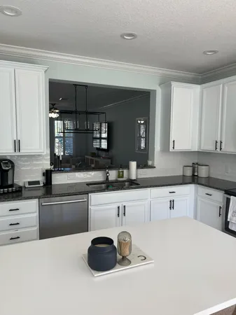 a kitchen with granite countertop a sink and white cabinets