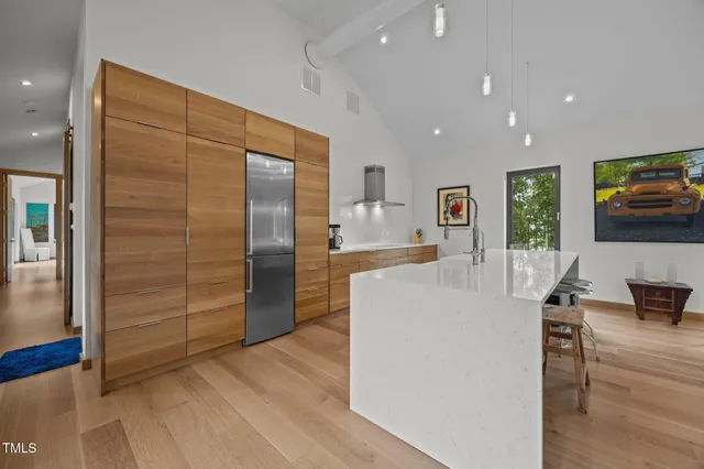 a living room with stainless steel appliances furniture refrigerator and a kitchen view