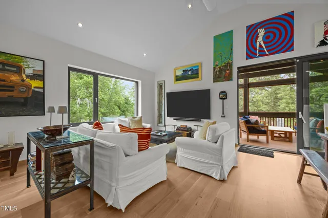 a living room with furniture a flat screen tv and a floor to ceiling window