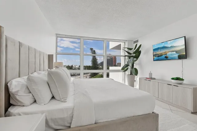 a living room with furniture a flat screen tv and a floor to ceiling window