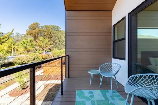 a view of hallway that has couch and a dining table with wooden floor