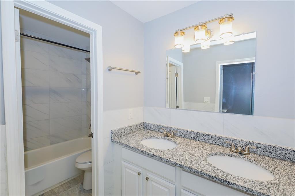 1277 Goodwin Road Northeast, Unit 1271 Atlanta, GA 30324 - Photo 13 of 19 a bathroom with a granite countertop sink mirror toilet and bathtub