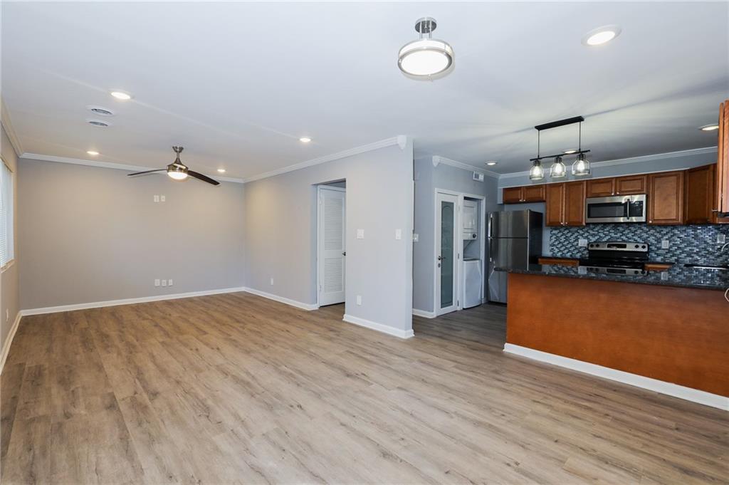 1277 Goodwin Road Northeast, Unit 1271 Atlanta, GA 30324 - Photo 7 of 19 an empty room with wooden floor and kitchen view