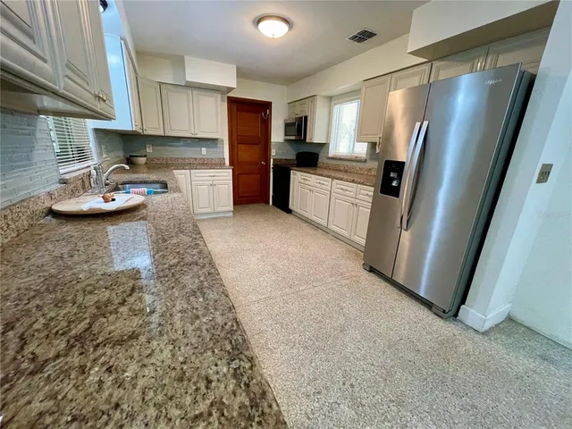 a kitchen with stainless steel appliances granite countertop a refrigerator and a stove